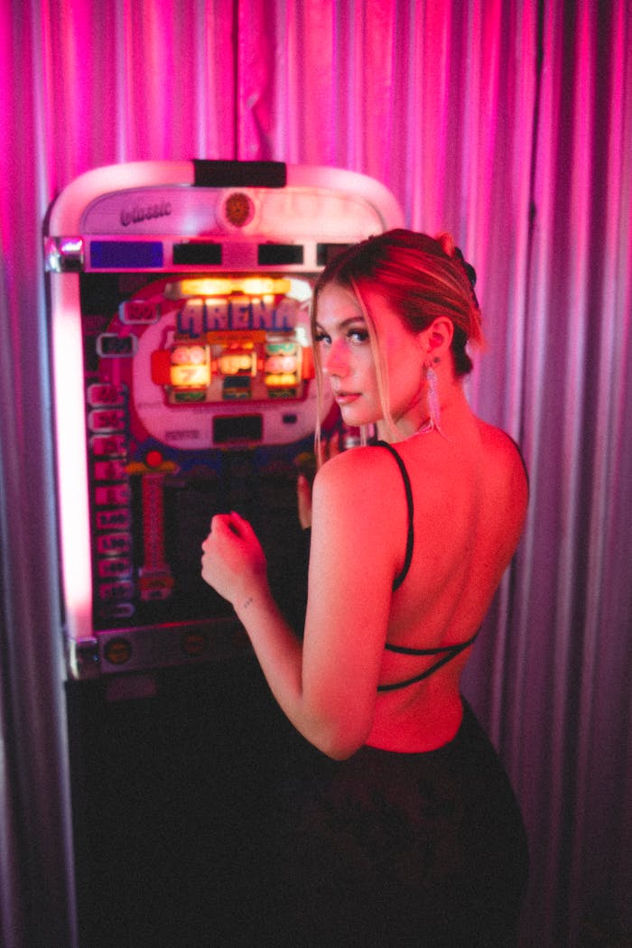Caucasian woman enjoying an evening at an amusement arcade with colorful lighting.