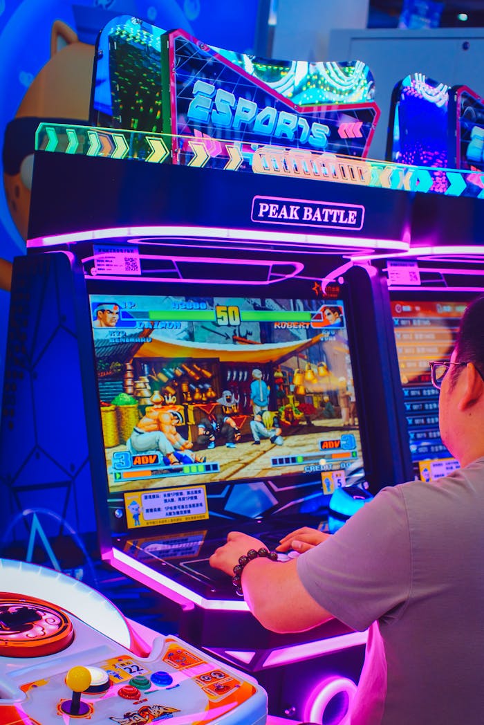 A person playing an arcade game in a vibrant, neon-lit setting at a gaming arcade.